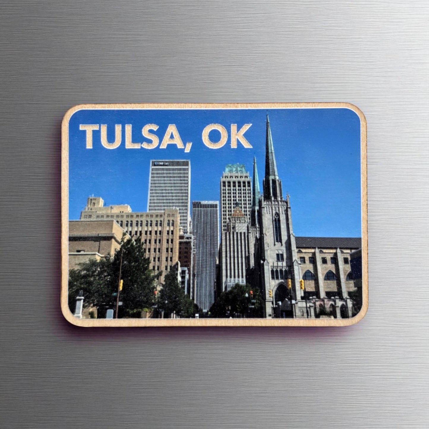 Downtown Tulsa skyline wood photo magnet on a metallic background, showing iconic Tulsa buildings and church spire with “TULSA, OK” printed at the top.
