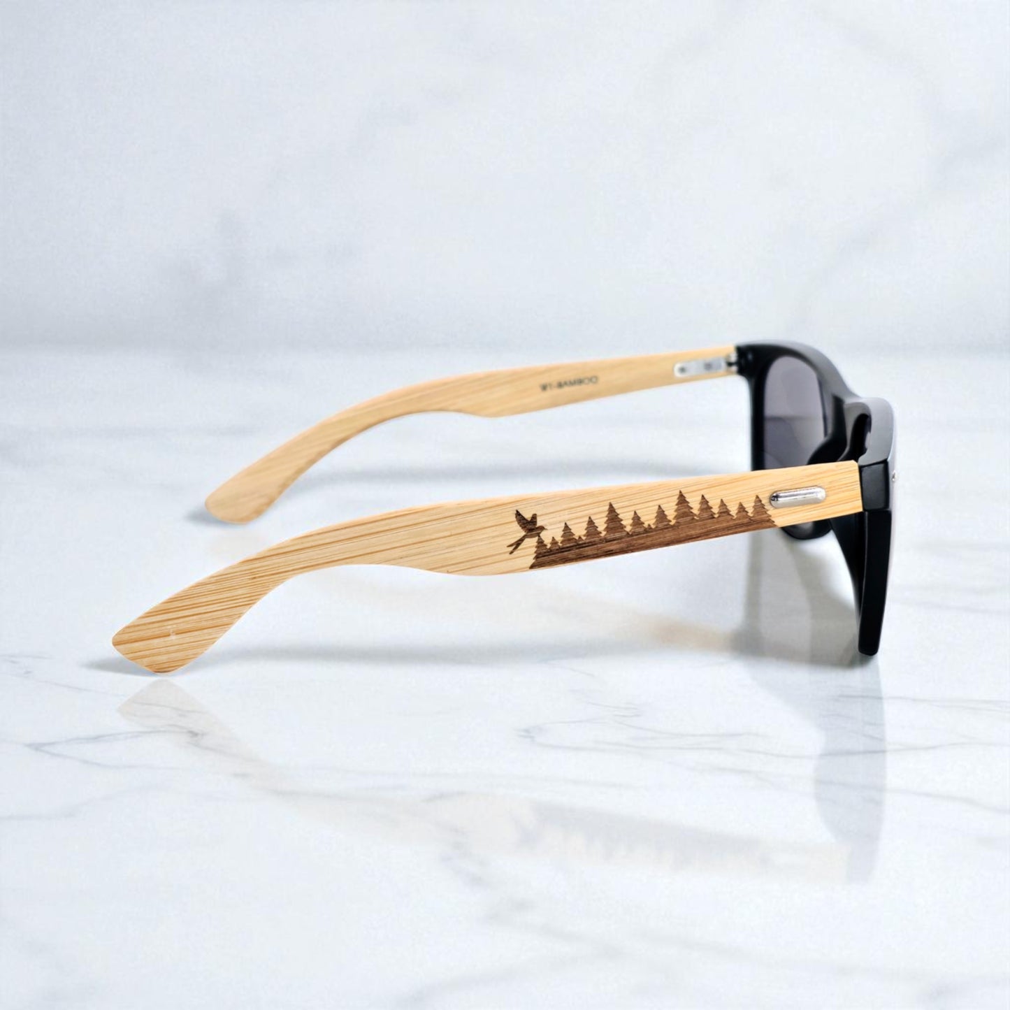 Laser-engraved bamboo sunglasses showcasing a serene pine forest silhouette with a flying bird, representing the peaceful woodlands of Oklahoma. These frames offer a rustic, outdoorsy aesthetic for nature-loving Oklahomans and travelers who appreciate unique, handcrafted eyewear.