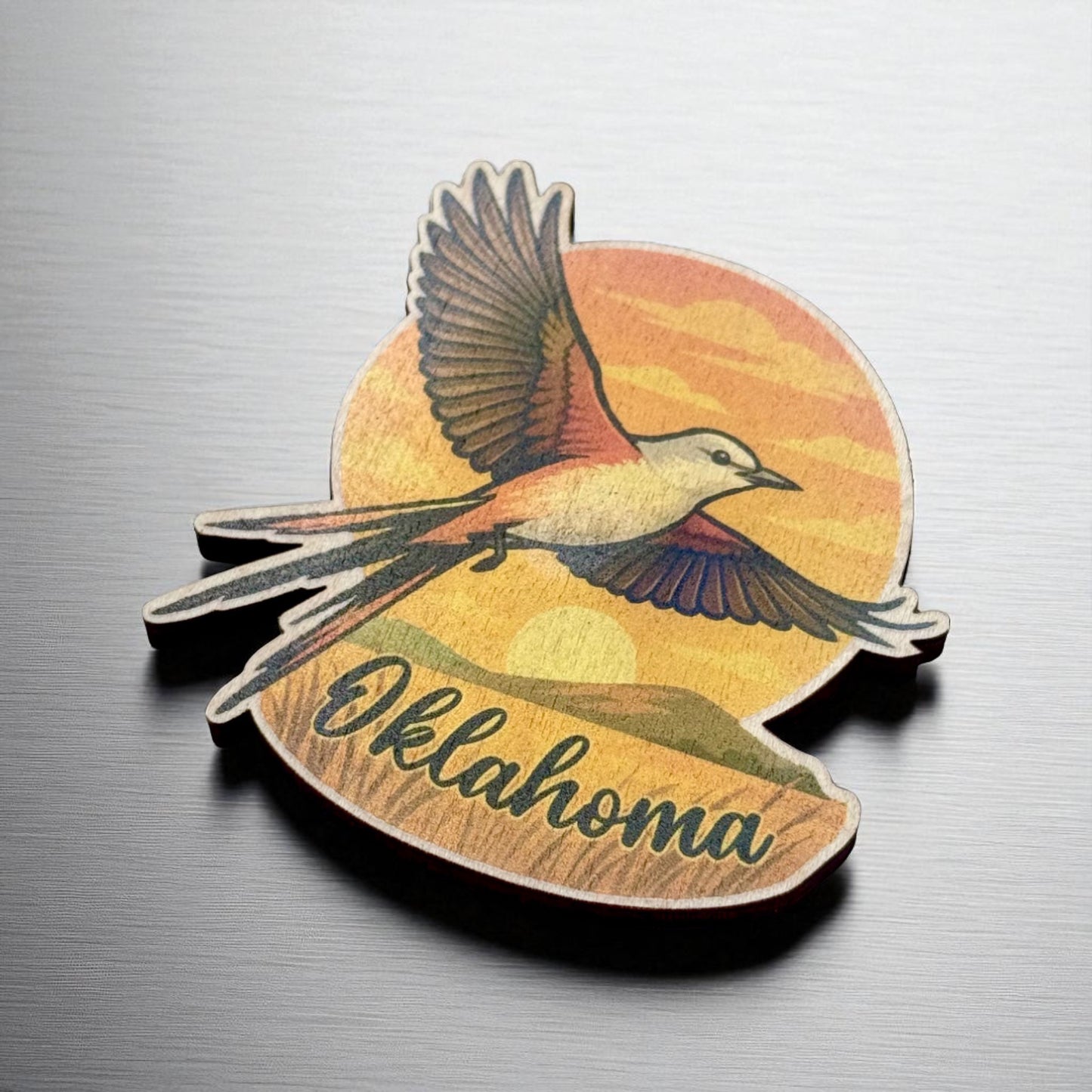 Angled view of maple wood magnet showing soaring state bird and bold Oklahoma script across a sunset landscape with rounded edge and precise cut