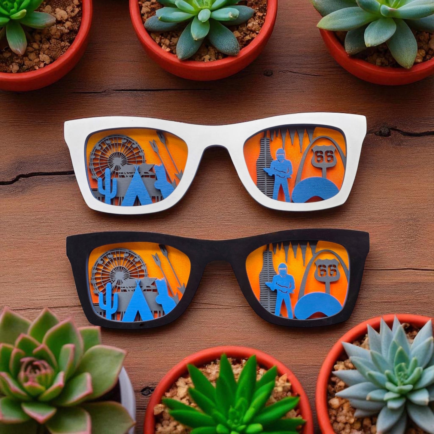 Top view of white and black wooden Route 66 skyline sunglasses wall decor surrounded by succulents, each frame filled with miniature cutouts of iconic landmarks along the historic highway.