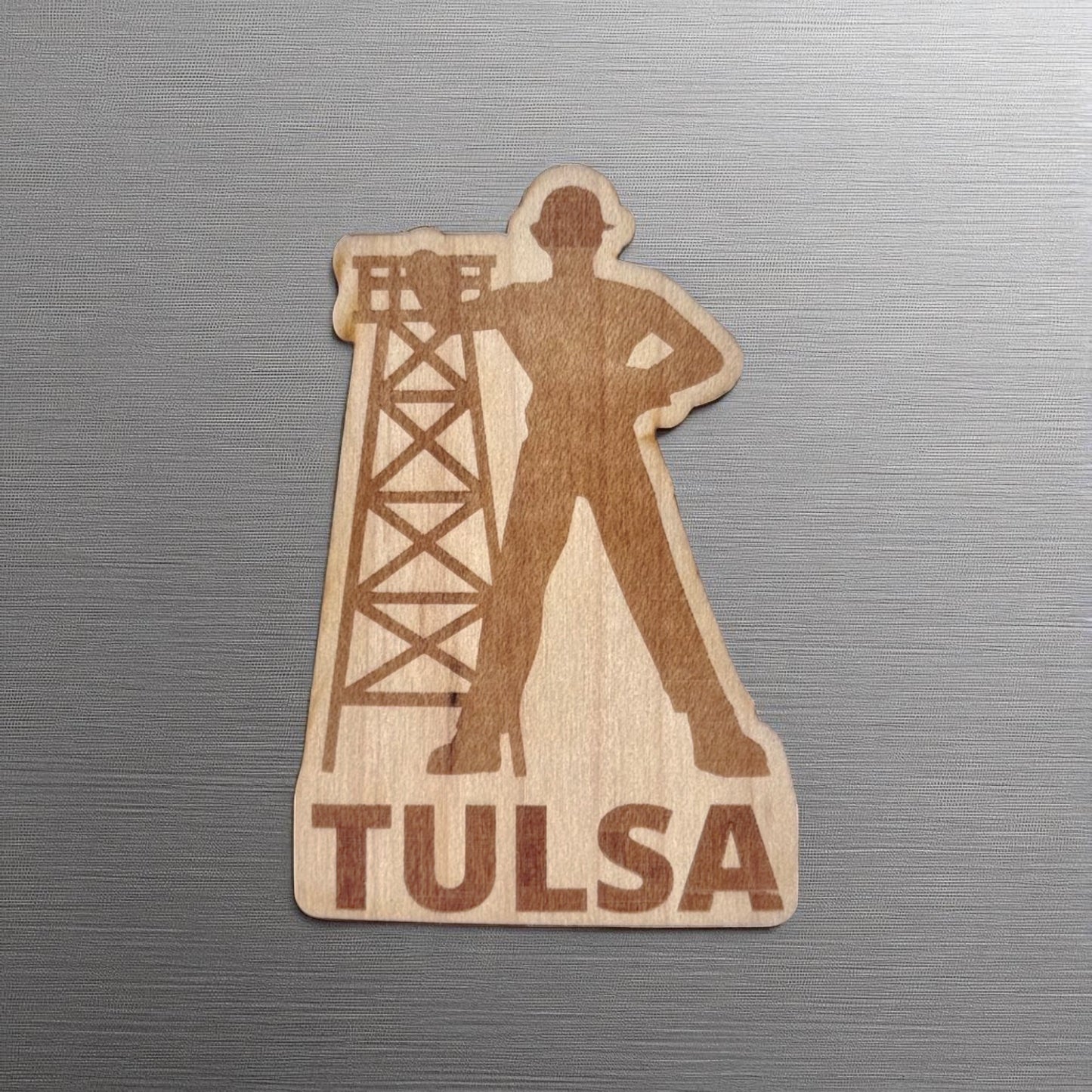 Golden Driller wood sticker featuring Tulsa’s iconic oil worker silhouette and rig, applied to a brushed metal laptop or water bottle