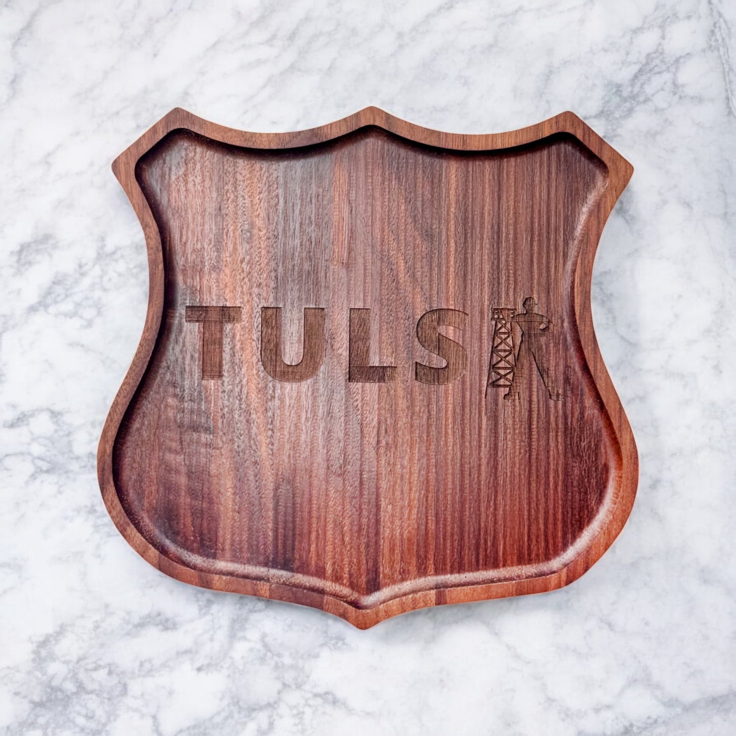 Front view of a walnut serving tray shaped like the Route 66 shield with engraved Tulsa Driller silhouette