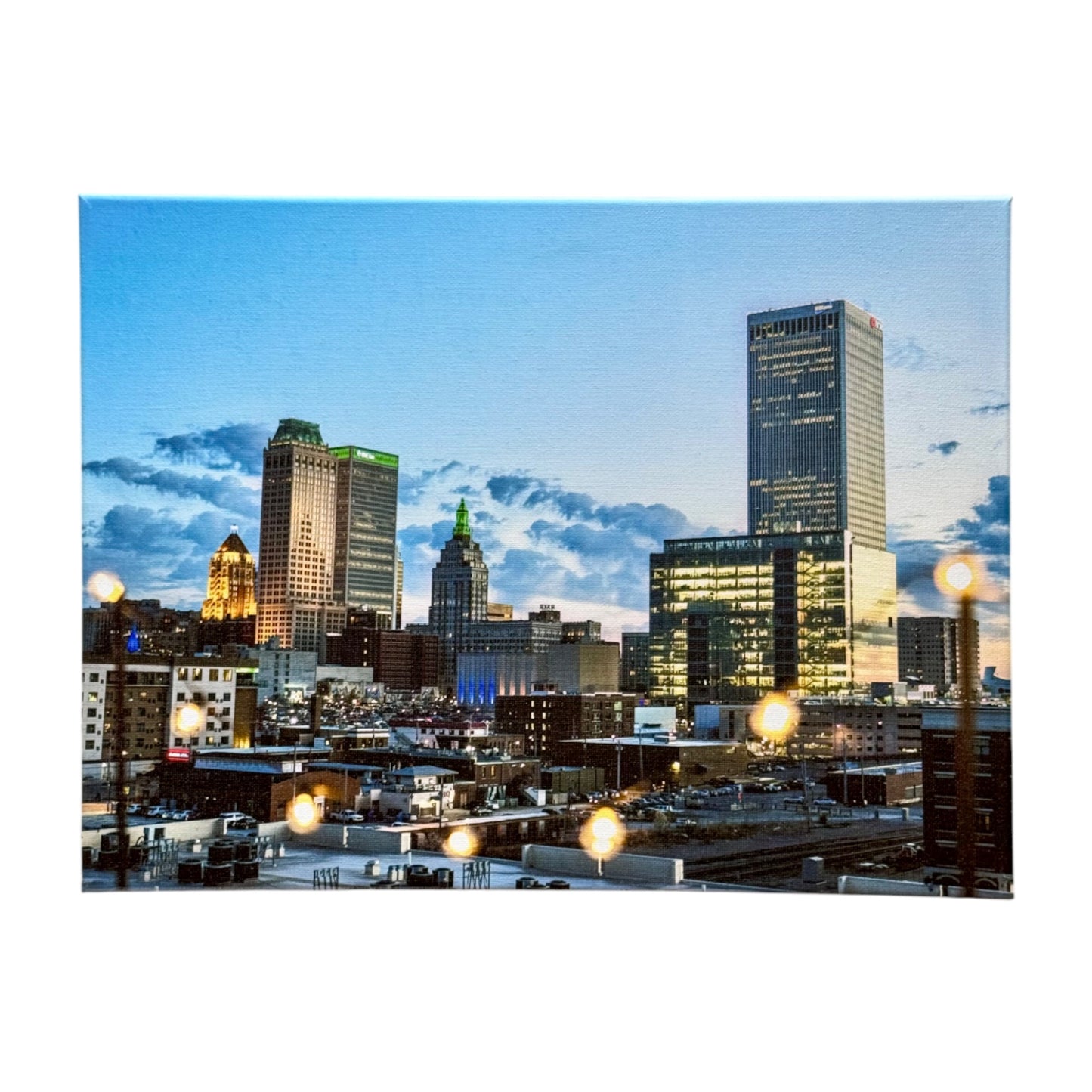 12x16 inch canvas of downtown Tulsa at dusk, featuring the skyline illuminated by city lights, with warm string lights softly reflecting off the surface.