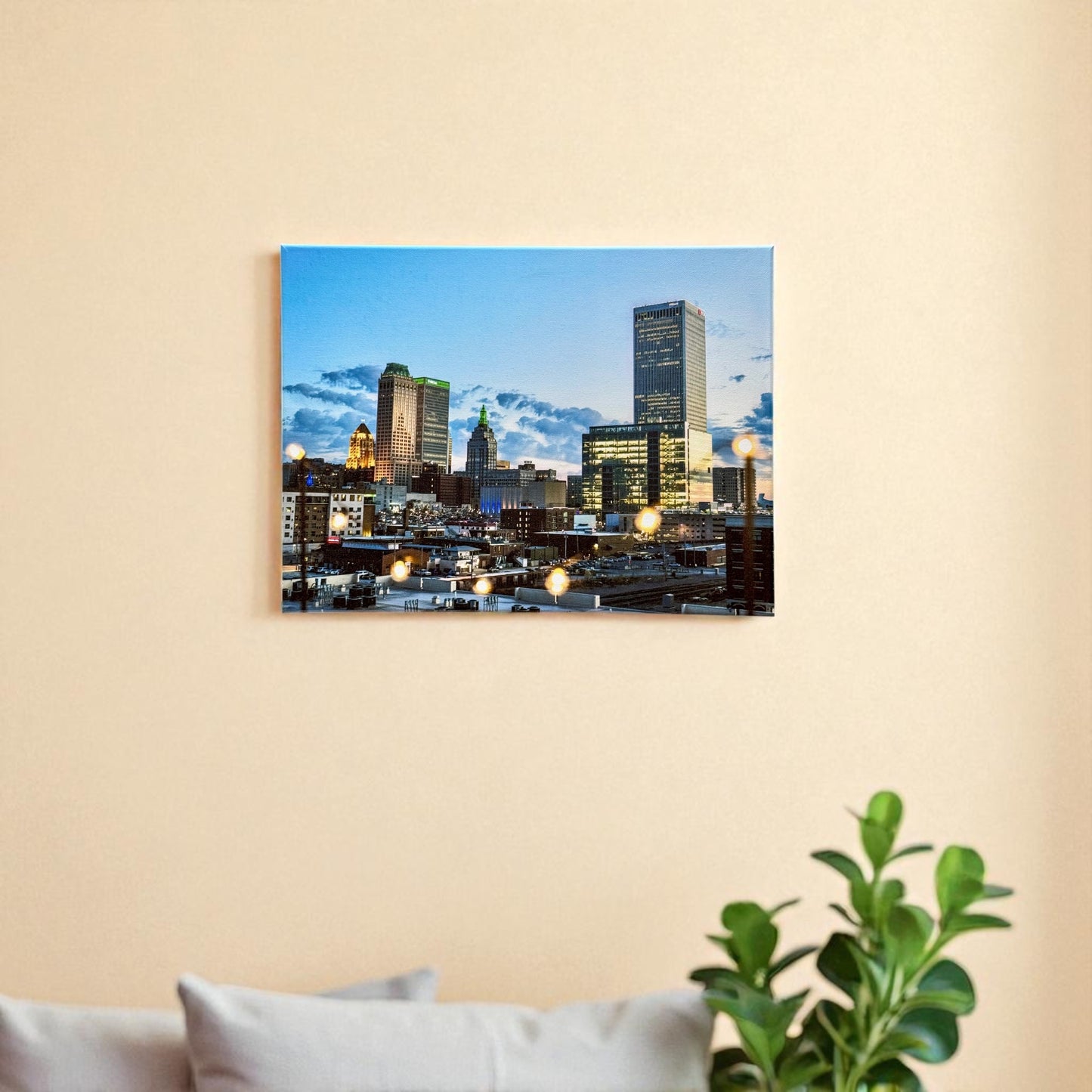 Wall-mounted 12x16 inch canvas of downtown Tulsa at dusk, featuring the skyline illuminated by city lights, with warm string lights softly reflecting off the surface.