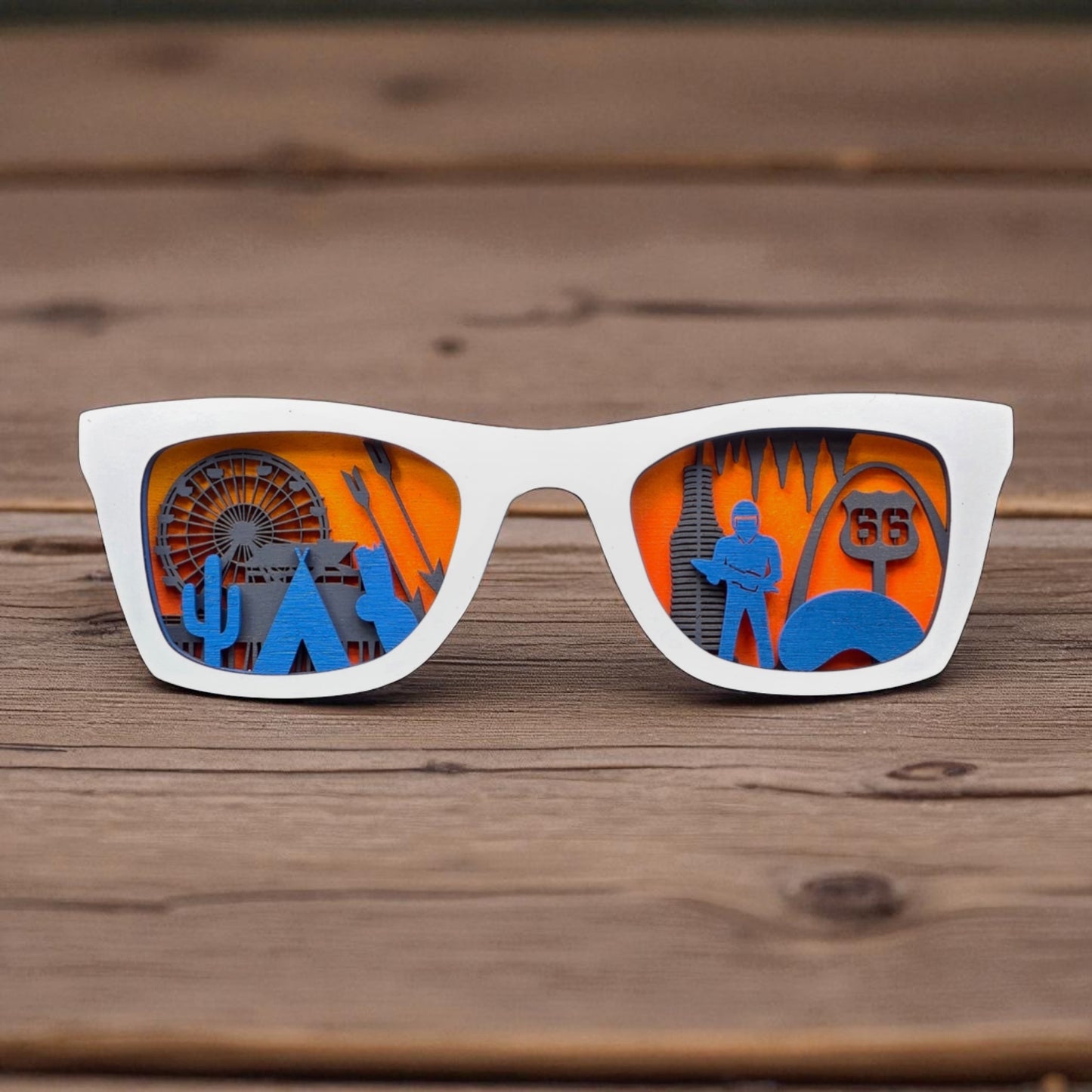 White wooden Route 66 skyline display glasses standing upright on a wooden table, with blue and gray layered wood cutouts of famous landmarks inside the lenses.