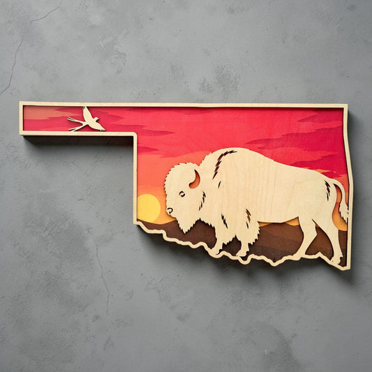 Oklahoma state shaped wall art with layered sunset design, large bison silhouette, and Scissortail Flycatcher displayed against gray wall background for Oklahoma souvenir and western decor