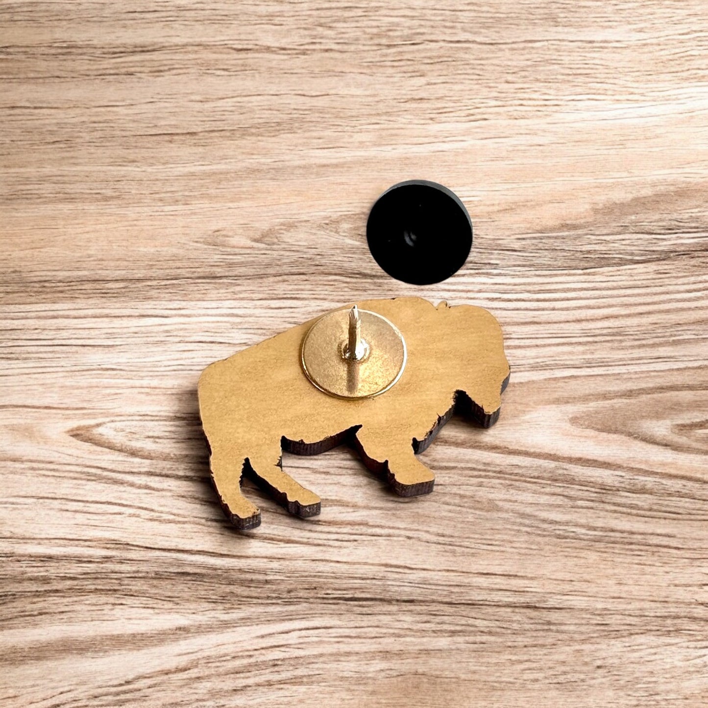 Back of Oklahoma American bison wooden pin showing metal post and black rubber pin back, lightweight wooden lapel pin for hats and jackets