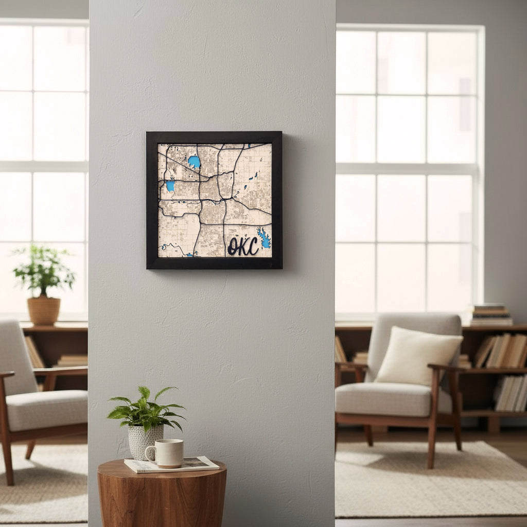 Framed layered Oklahoma City wooden map mounted on an interior wall between windows, detailed OKC street map wall art with blue water features, modern Oklahoma City decor