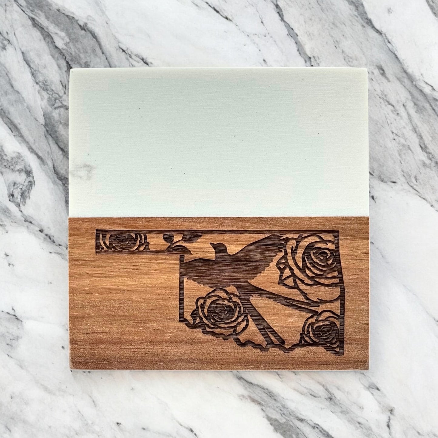 Marble and acacia wood coaster engraved with Oklahoma state outline, Scissortail Flycatcher, and rose details, photographed on white marble background
