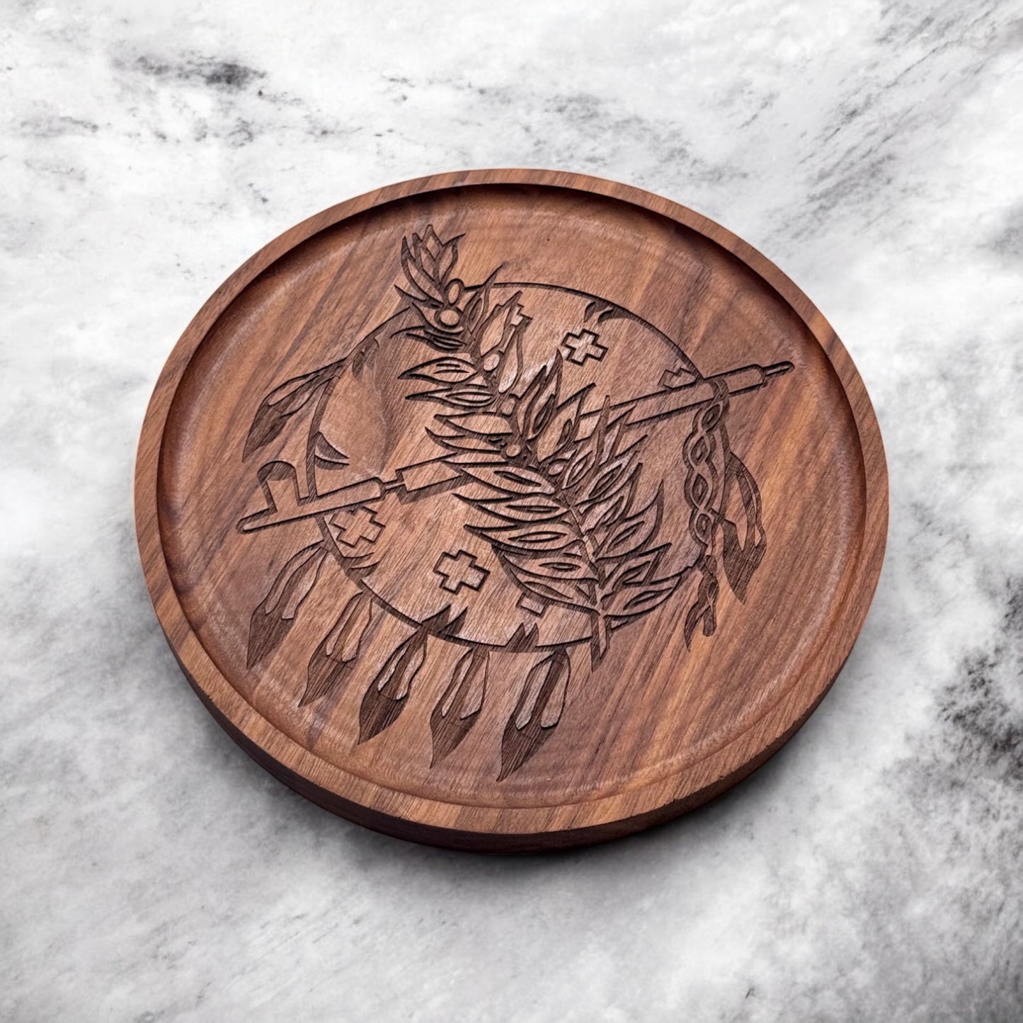 Top-down view of round walnut tray engraved with the Oklahoma state symbol featuring feathers, a calumet, and olive branch