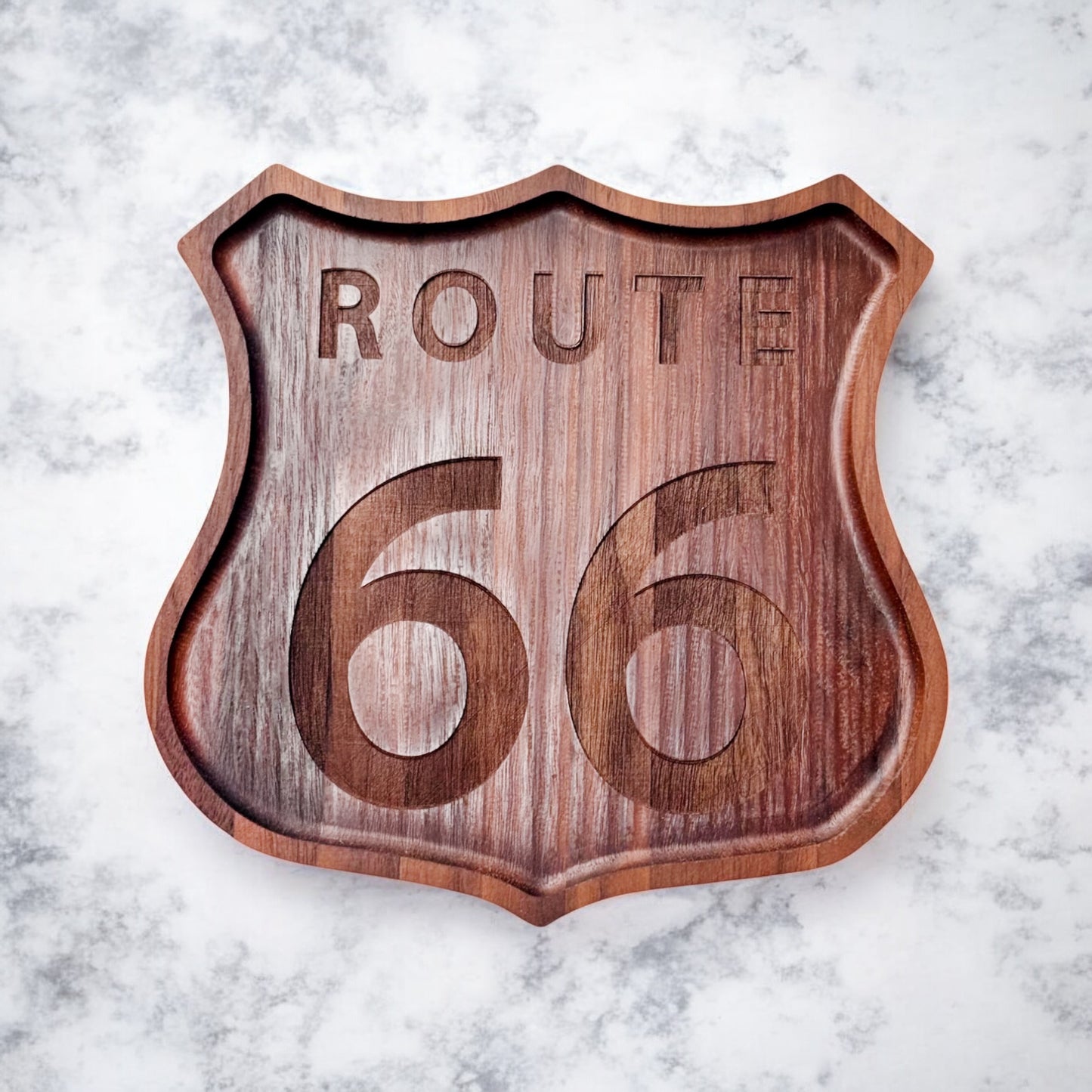 Flatlay of solid walnut Route 66 shield tray with engraved numbers and text, on marble background