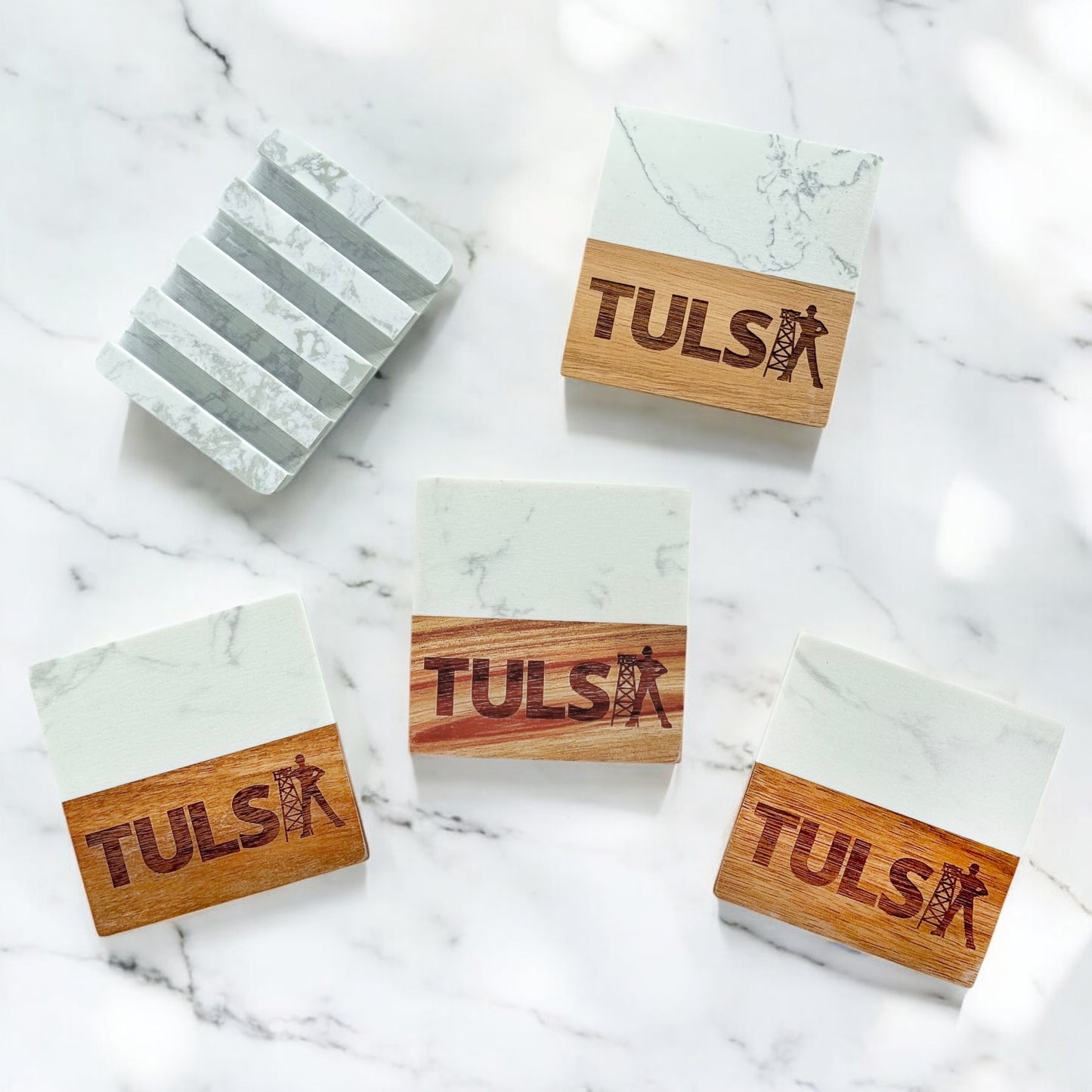Four Tulsa coasters with laser-engraved Golden Driller design, displayed with matching marble base on white marble surface.