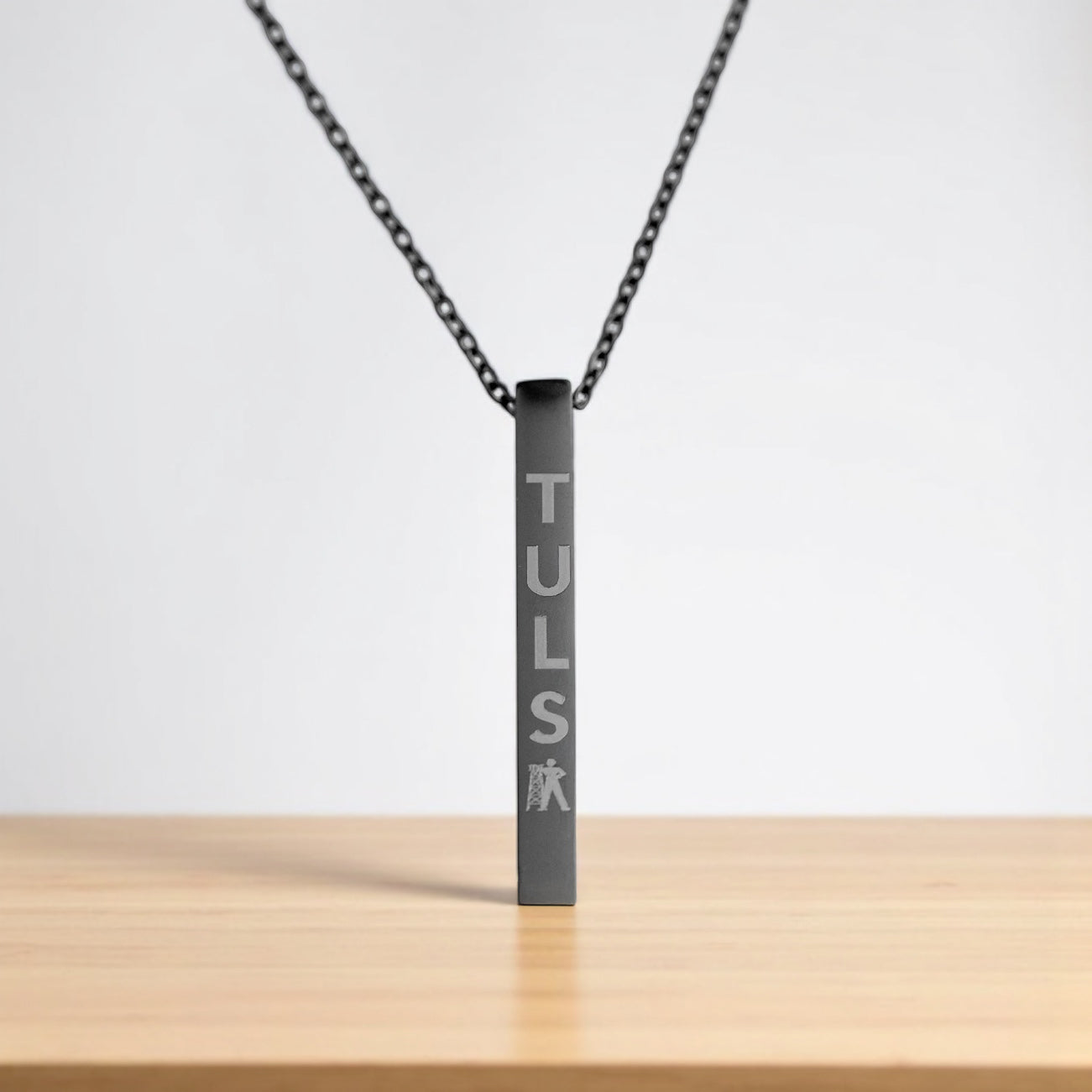 Close-up of matte black Tulsa Driller necklace with vertical engraving, urban-inspired gift from Oklahoma