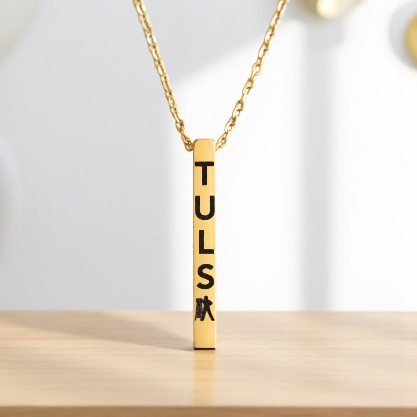 Close-up of gold Tulsa necklace with Driller figure, engraved bar pendant for Oklahoma lovers