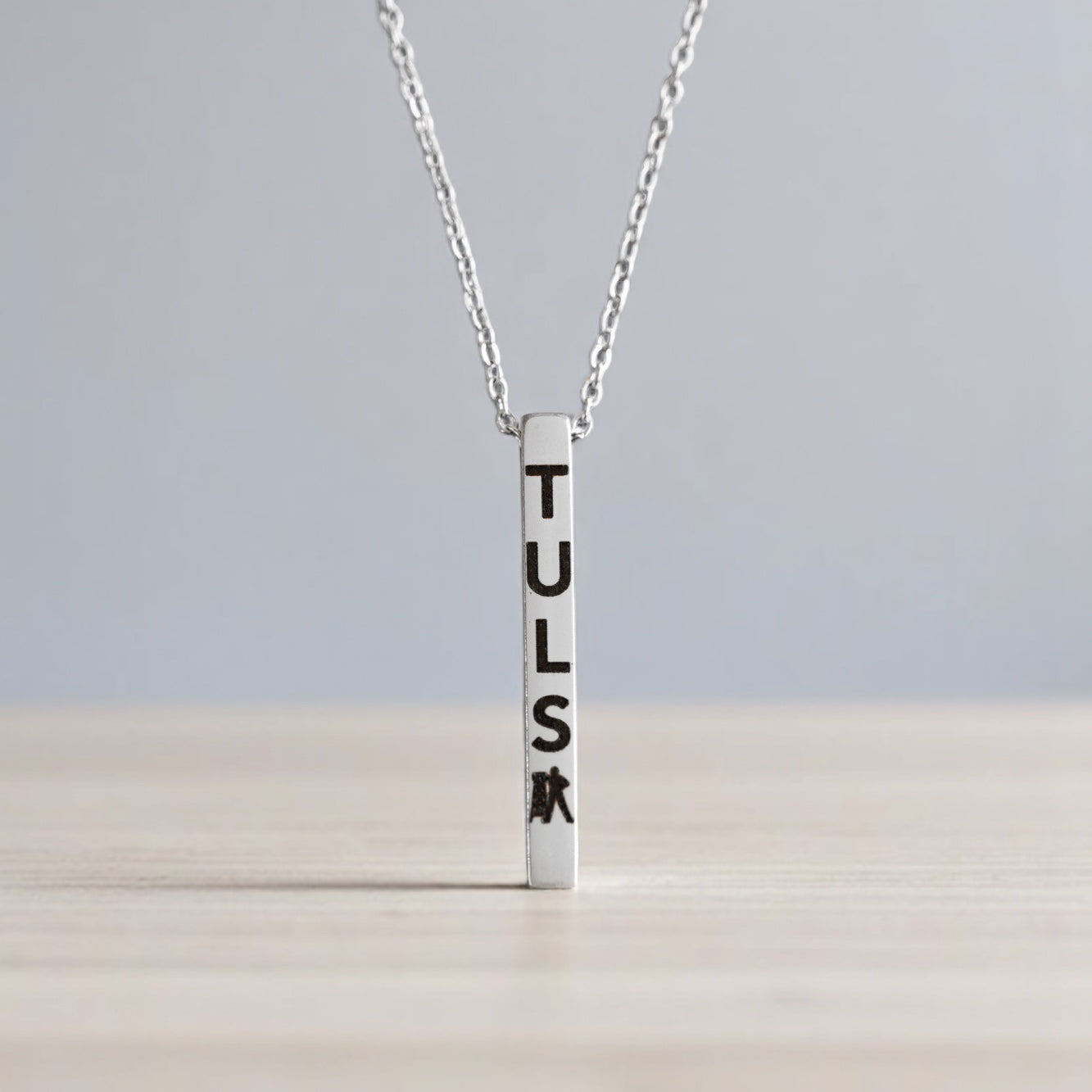 Detail of silver bar pendant engraved with TULSA and Driller symbol, elegant Tulsa-themed jewelry