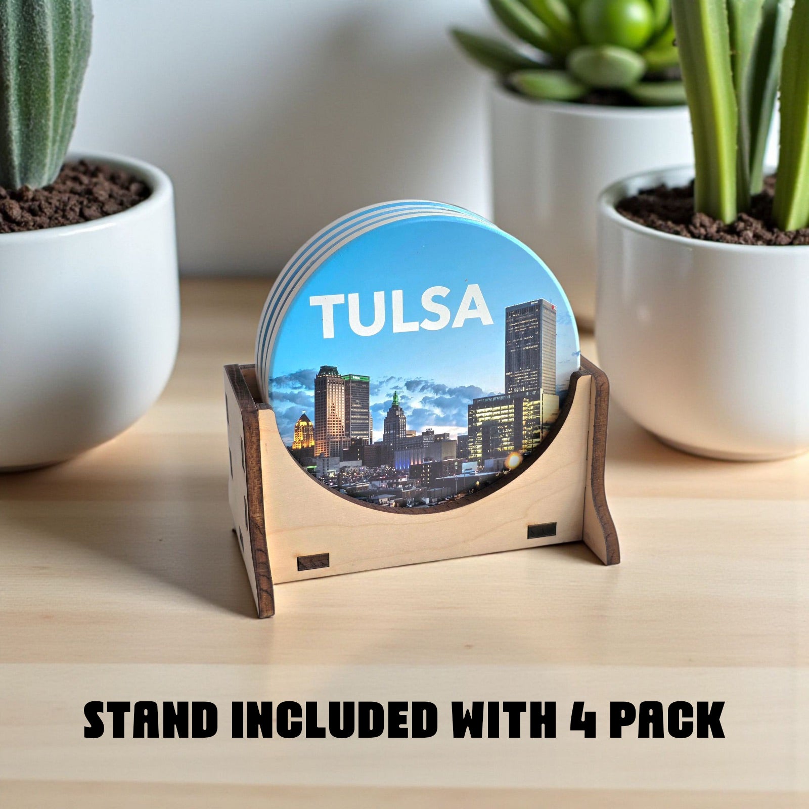 Coaster set with Tulsa skyline design on a wooden stand, surrounded by potted plants.