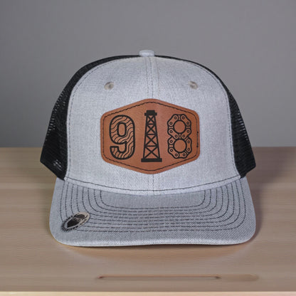 Close up of 918 Tulsa leatherette patch showing engraved oil derrick and textured numbers on trucker hat