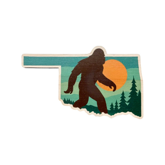 Oklahoma shaped maple wood fridge magnet with Bigfoot silhouette walking through a forest at sunset printed in bold colorful detail
