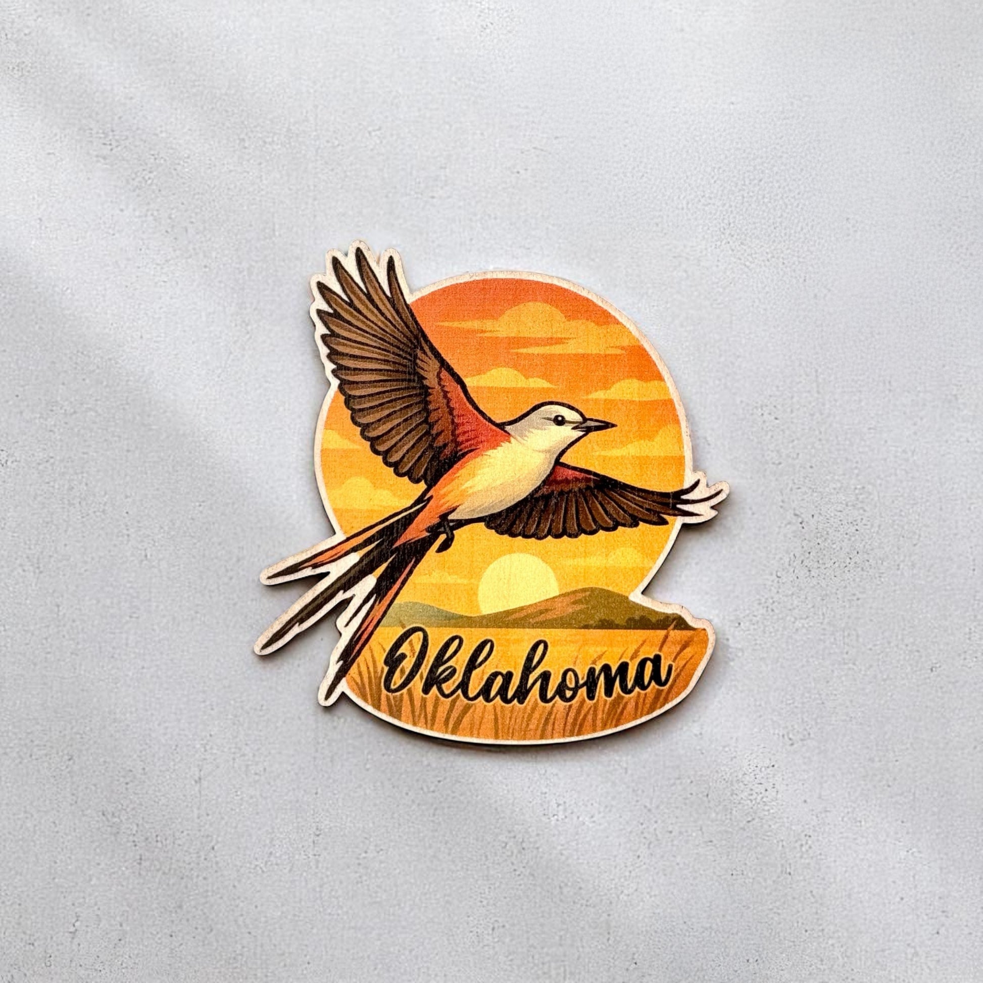 Vibrant Oklahoma wood sticker featuring a flying Scissor-tailed Flycatcher with sunset and landscape background, perfect for journals or laptops