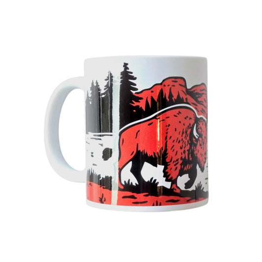 White ceramic mug with bold bison, forest, and mountain design on white background.