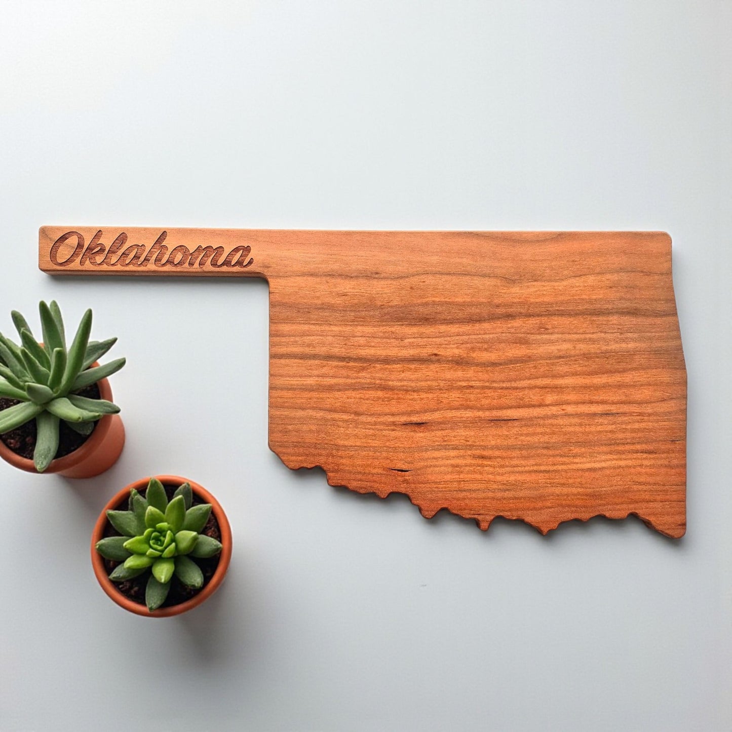 Overhead view of cherry wood Oklahoma charcuterie board with engraved script.