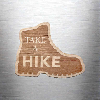 “Take a Hike” hiking boot wood sticker applied to a brushed metal water bottle or laptop, showing natural wood grain detail