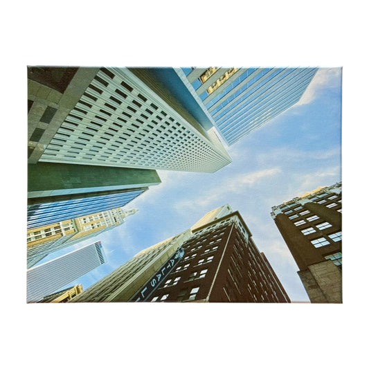 Canvas print featuring an upward view of Tulsa’s downtown skyscrapers against a blue sky, photographed from a low angle and displayed on a white background