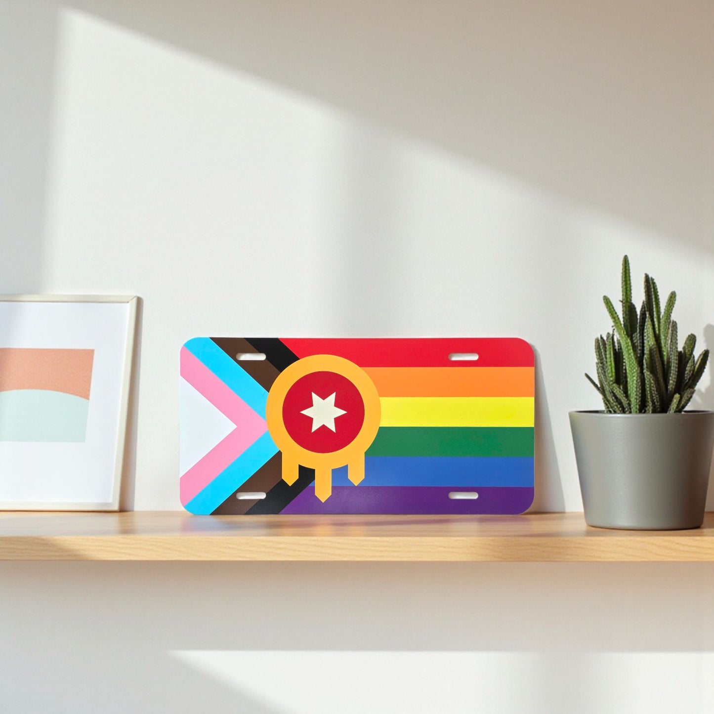 Tulsa inclusive LGBTQ license plate displayed on a wooden shelf next to a cactus plant.
