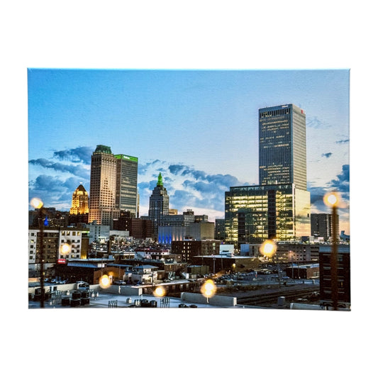 12x16 inch canvas of downtown Tulsa at dusk, featuring the skyline illuminated by city lights, with warm string lights softly reflecting off the surface.