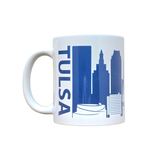 White ceramic mug featuring navy Tulsa skyline silhouette with Golden Driller and city buildings.