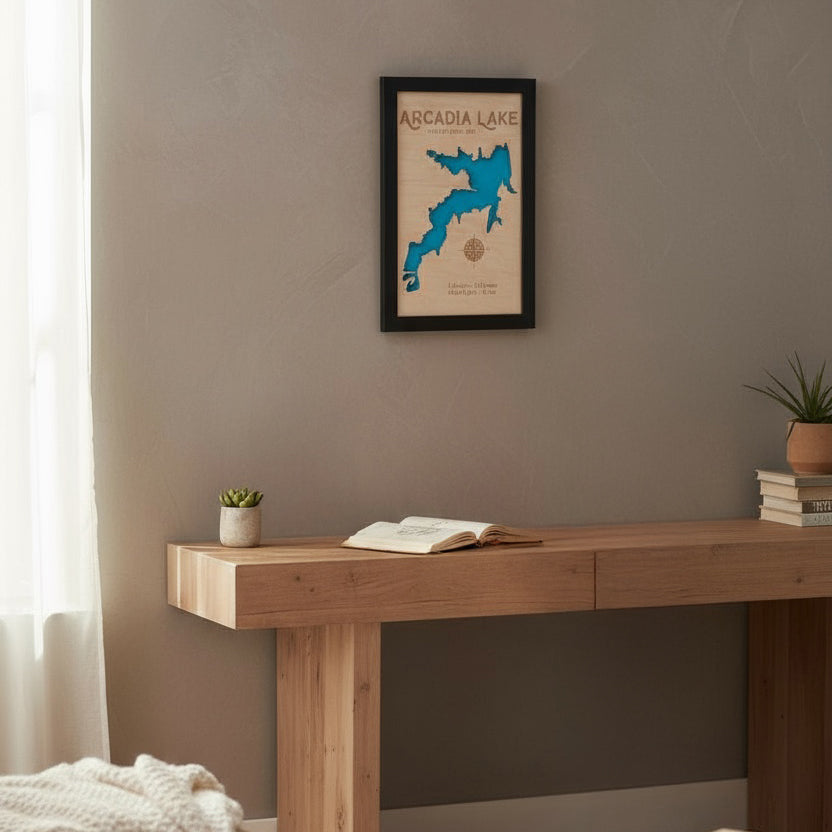 Framed Arcadia Lake layered wood map hanging on a wall above a wooden table, showcasing handmade Oklahoma lake decor for home or cabin.