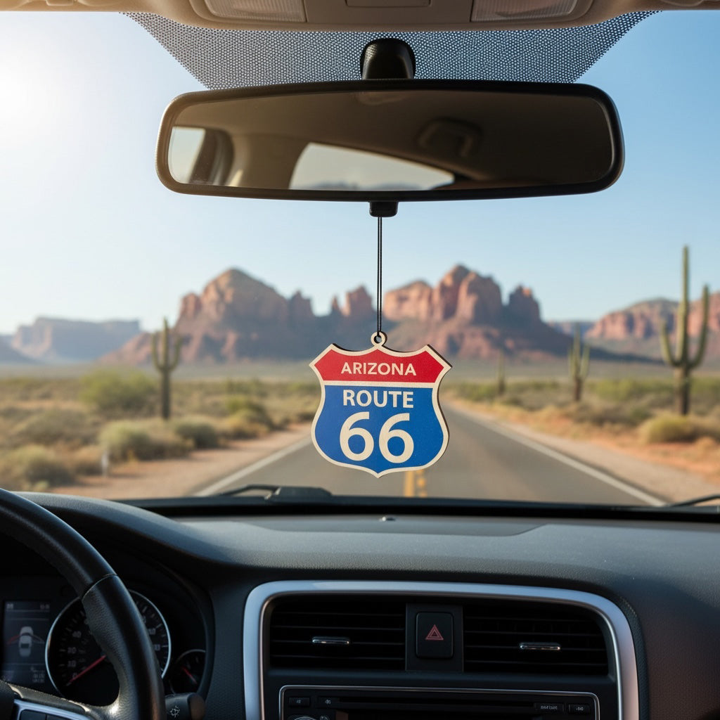 Arizona Route 66 shield ornament hanging from a car rearview mirror with desert highway scenery, cactus landscape, and red rock formations inspired by Southwest Route 66 travel