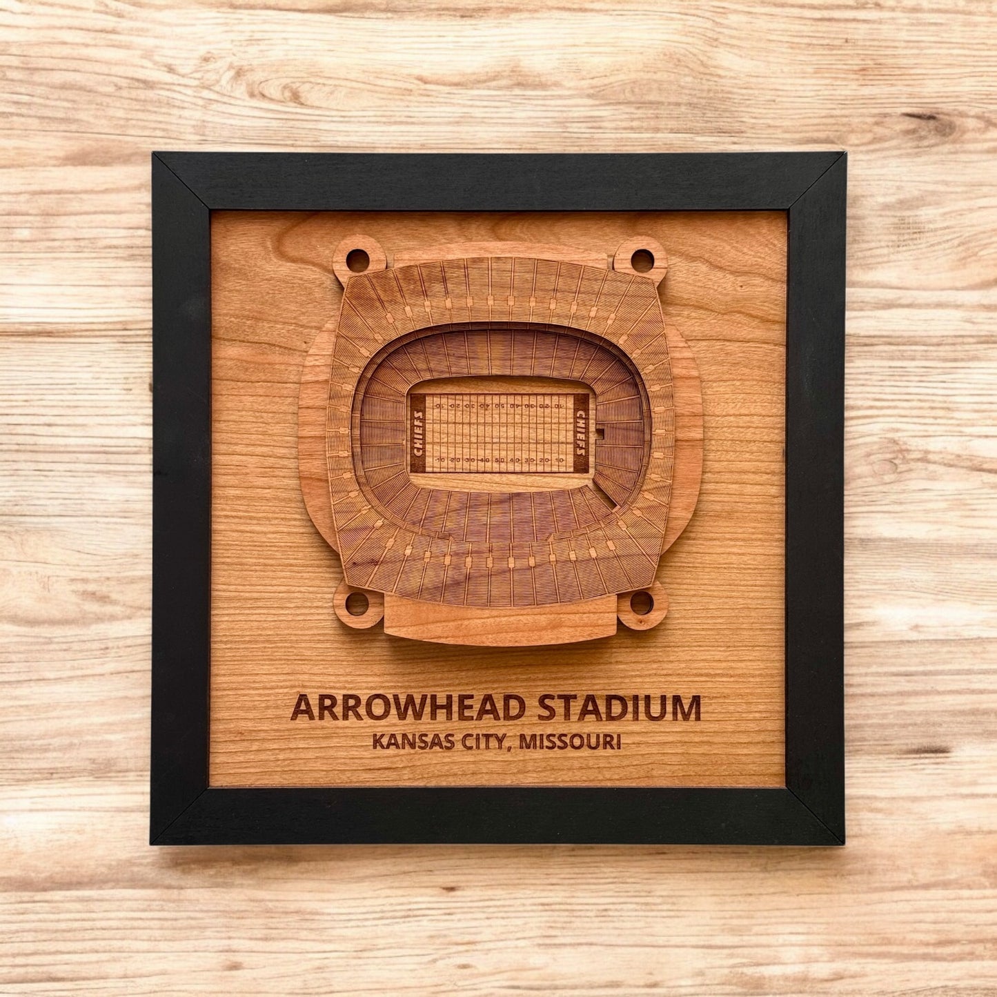 Flat lay of framed Arrowhead Stadium wooden wall art on a wood surface