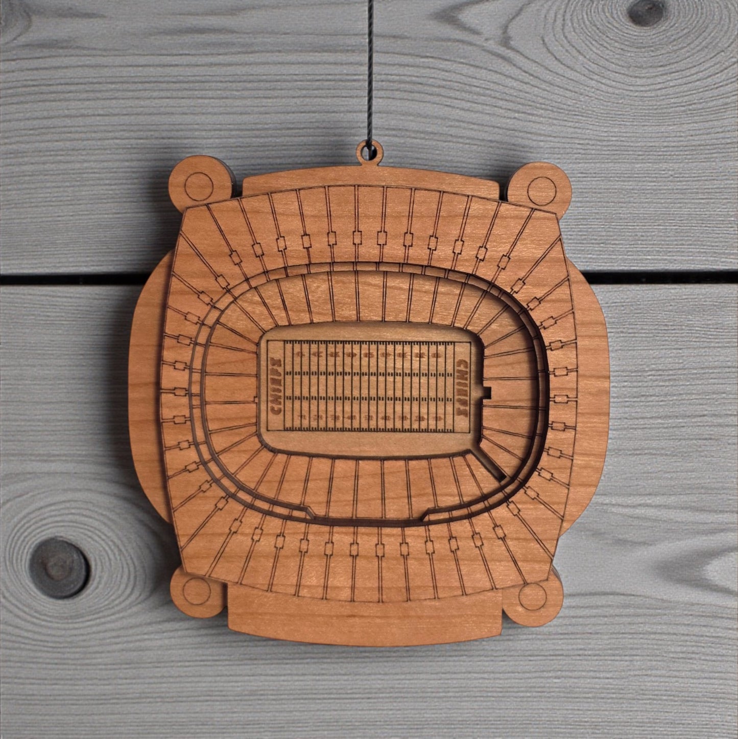 Close up of Arrowhead Stadium wooden ornament showing engraved seating sections and layered wood construction, detailed Kansas City football stadium ornament