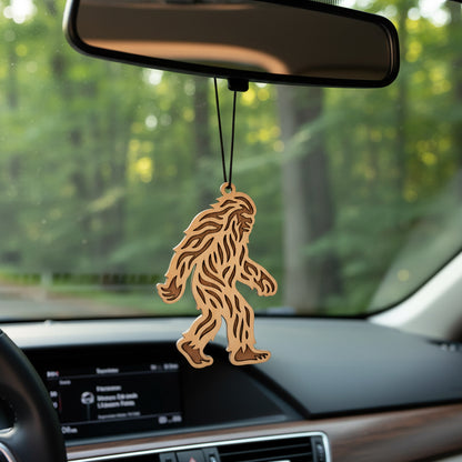 Laser cut wooden Bigfoot car ornament hanging from rearview mirror, textured Sasquatch silhouette design with black cord, lightweight wood auto accessory gift for road trip lovers, national park travelers, and Bigfoot fans in the USA
