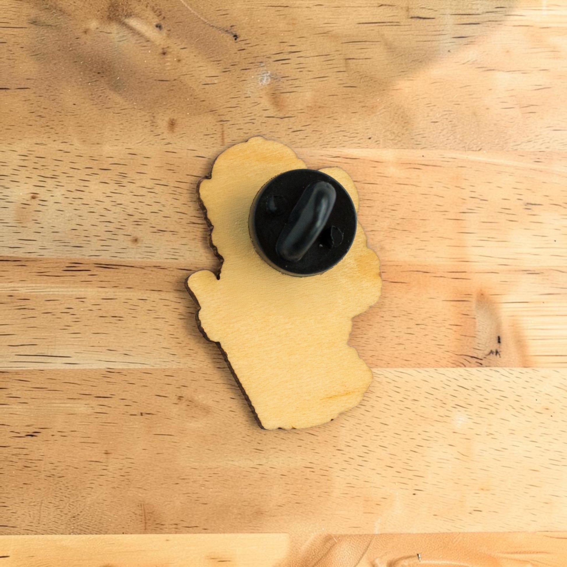 Back side of bison wooden lapel pin showing secure rubber backing on Eco Wood Birch shaped mascot pin displayed on wood surface