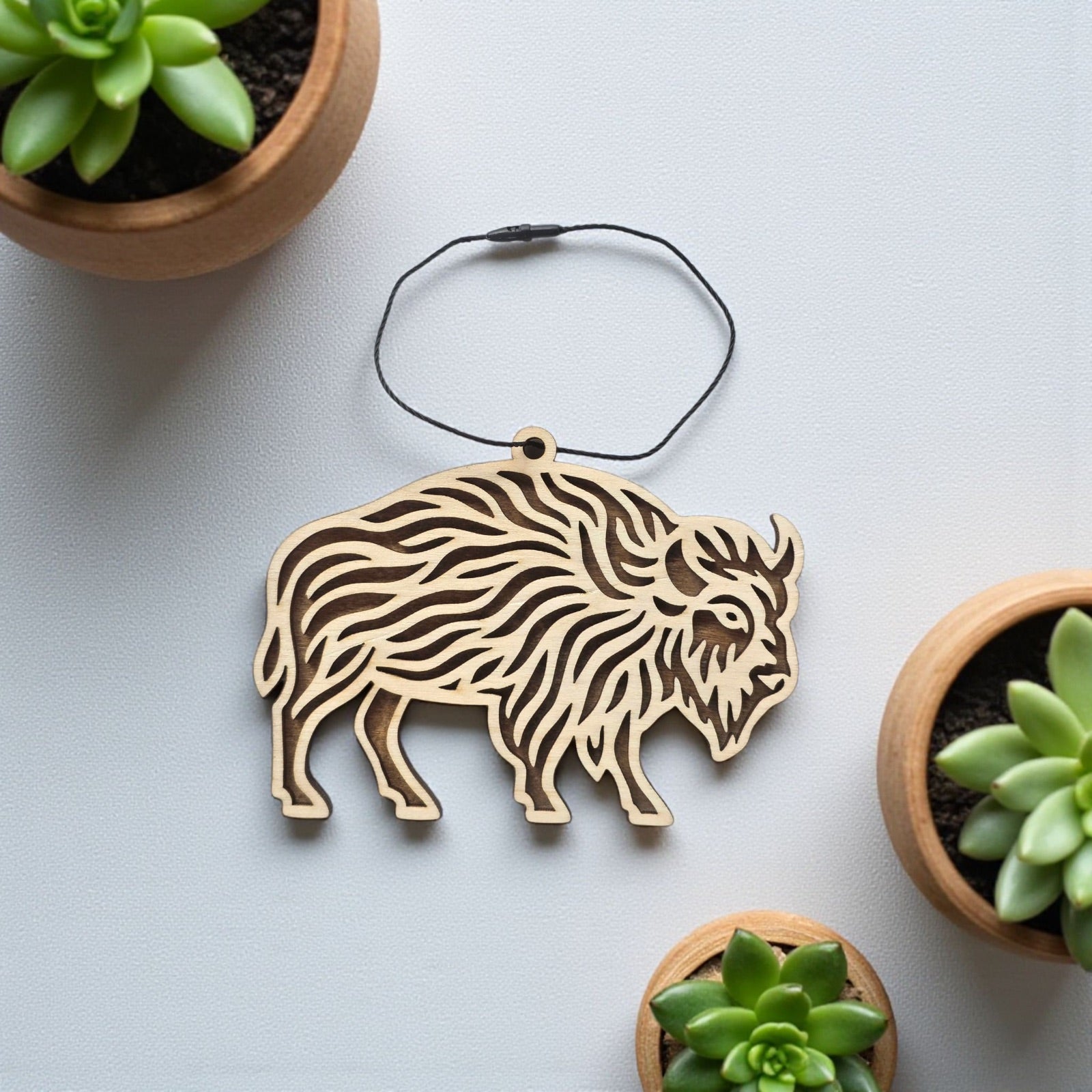 Flat lay of layered bison wooden ornament showing cut out front layer and stained back silhouette, natural wood wildlife decor