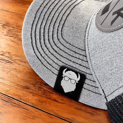 Aluminum Bison logo hat clip attached to the brim of a gray hat, square decorative clip worn as a subtle accessory