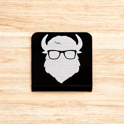 Flat lay of aluminum Bison logo hat clip showing square shape and brushed metal finish on black background