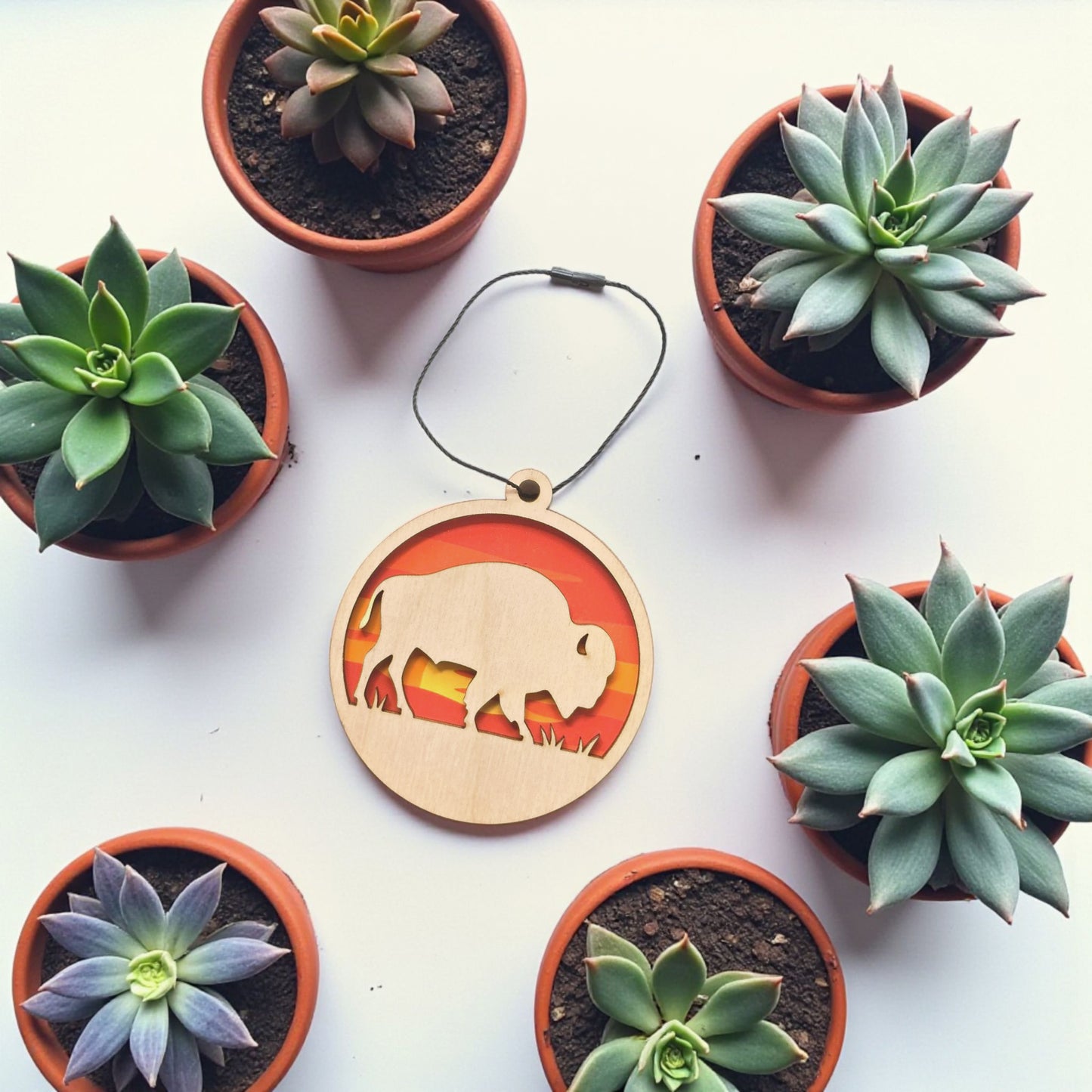 Flat lay of bison sunset wooden ornament showing layered construction with natural wood front and colorful sunset background