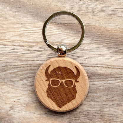 Bison wooden keychain displayed on wood surface, laser engraved Curious Bison icon on round wooden keychain for everyday carry