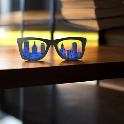 Black frame Tulsa skyline sunglasses decor displayed on a wooden shelf with books in the background