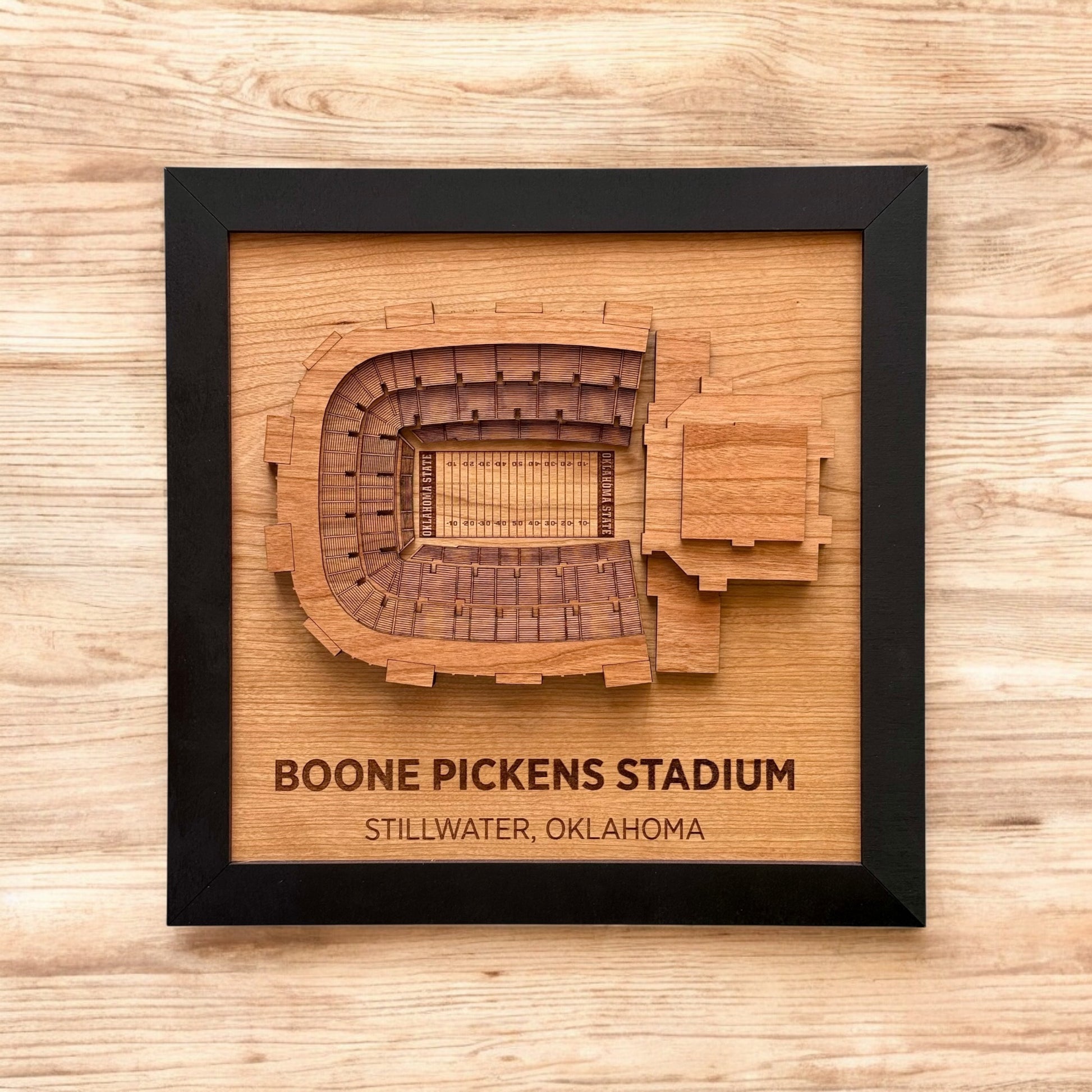Framed wooden wall art featuring a top down view of Boone Pickens Stadium with engraved stadium name
