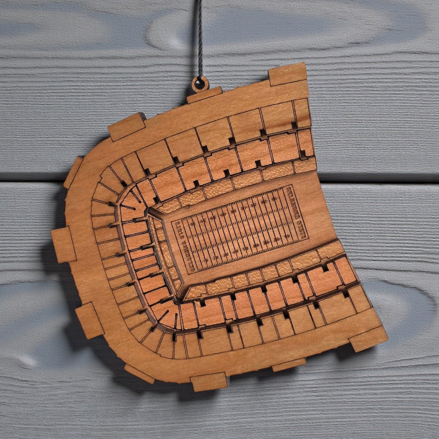Close up of Boone Pickens Stadium wooden ornament showing engraved seating sections and layered wood construction, detailed Oklahoma State Cowboys stadium ornament
