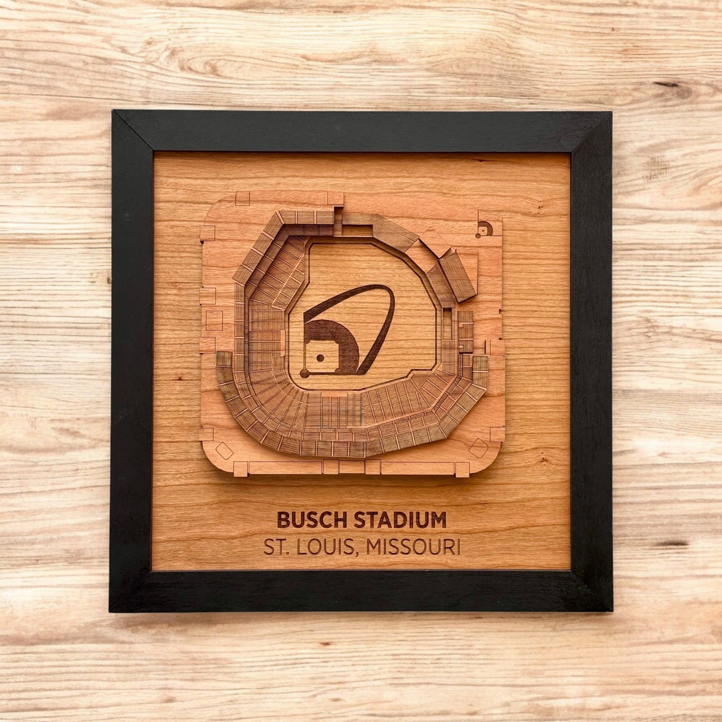 Flat lay of framed Busch Stadium wooden wall art on a wood surface