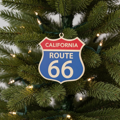 California Route 66 wooden ornament hanging on a Christmas tree with warm lights, nostalgic highway sign ornament for Route 66 travelers and California souvenir collectors