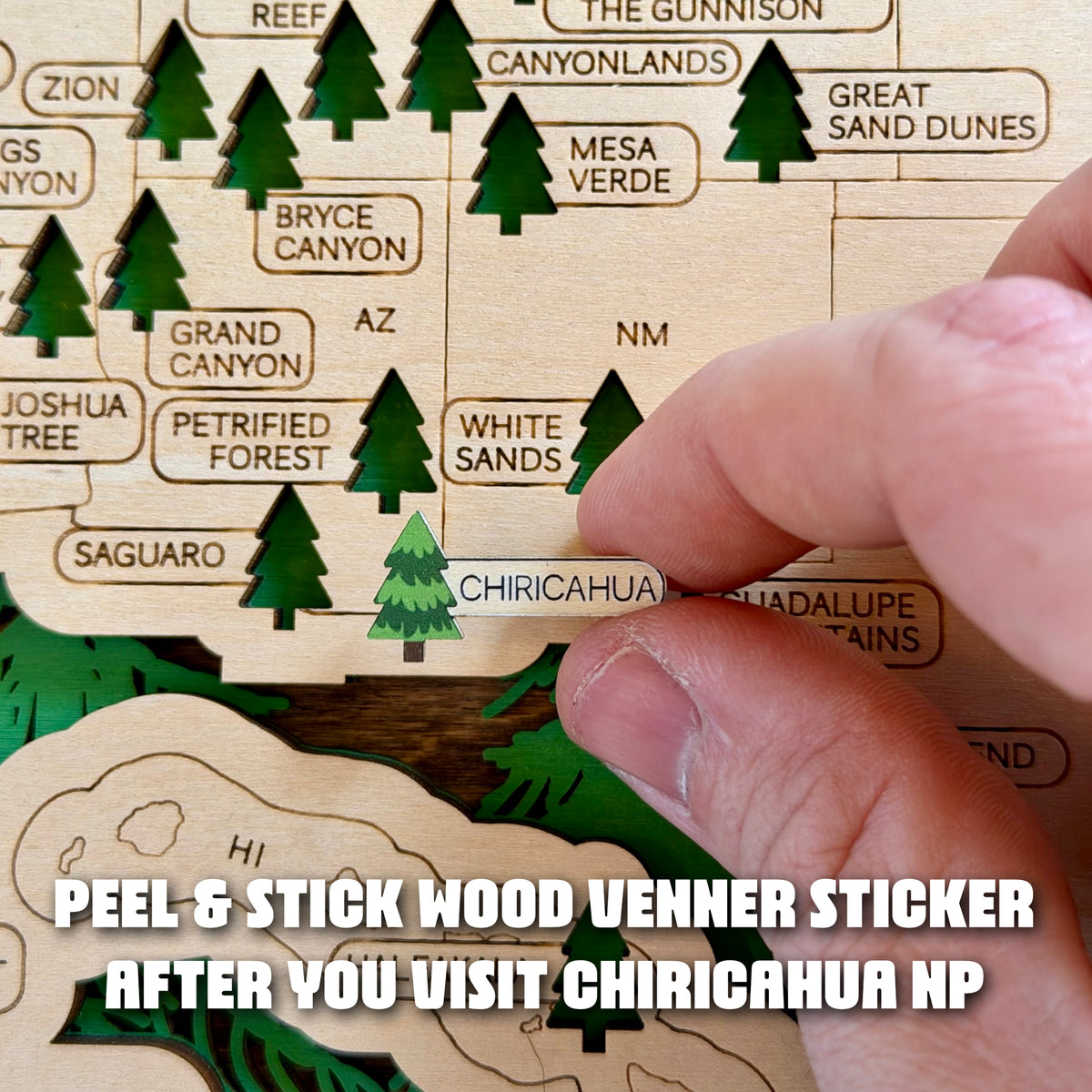 Close-up of a hand positioning the Chiricahua National Park peel-and-stick wood veneer marker on a wooden USA National Parks Travel Map in southeastern Arizona, showing how the 64th park can be added to an existing travel tracker.