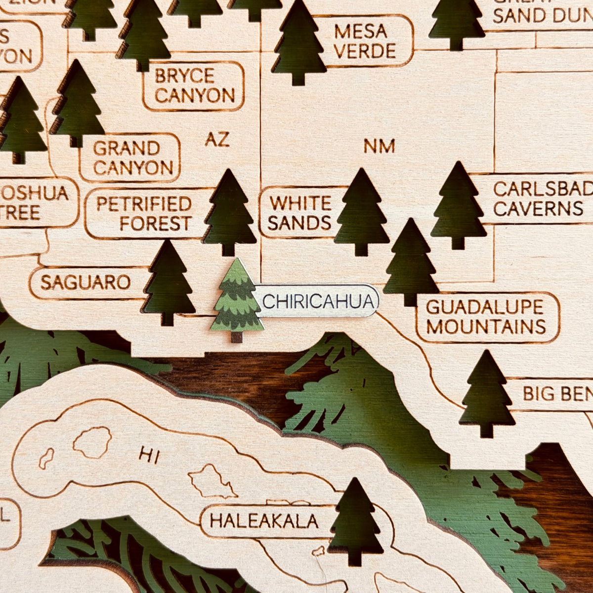 Close-up of Chiricahua National Park wood veneer sticker installed on a wooden National Parks Travel Map near Saguaro, White Sands, and Guadalupe Mountains, showing the green tree marker and slightly raised wooden nameplate.