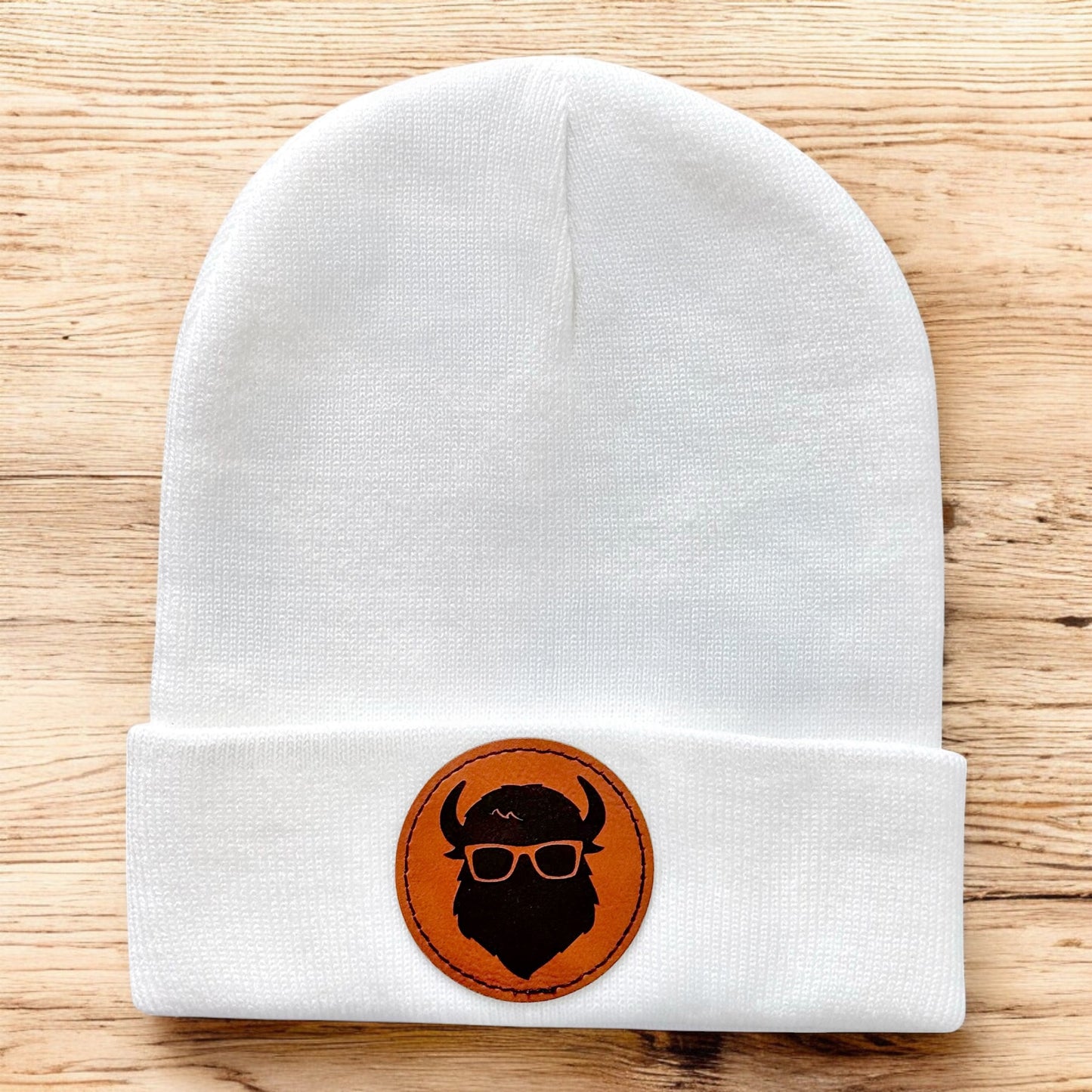 White knit beanie with Curious Bison leatherette patch and bison logo, minimalist winter hat designed for Tulsa souvenir gifting