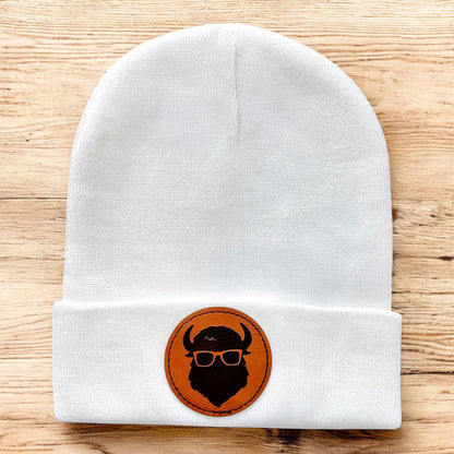 White knit beanie with Curious Bison leatherette patch and bison logo, minimalist winter hat designed for Tulsa souvenir gifting